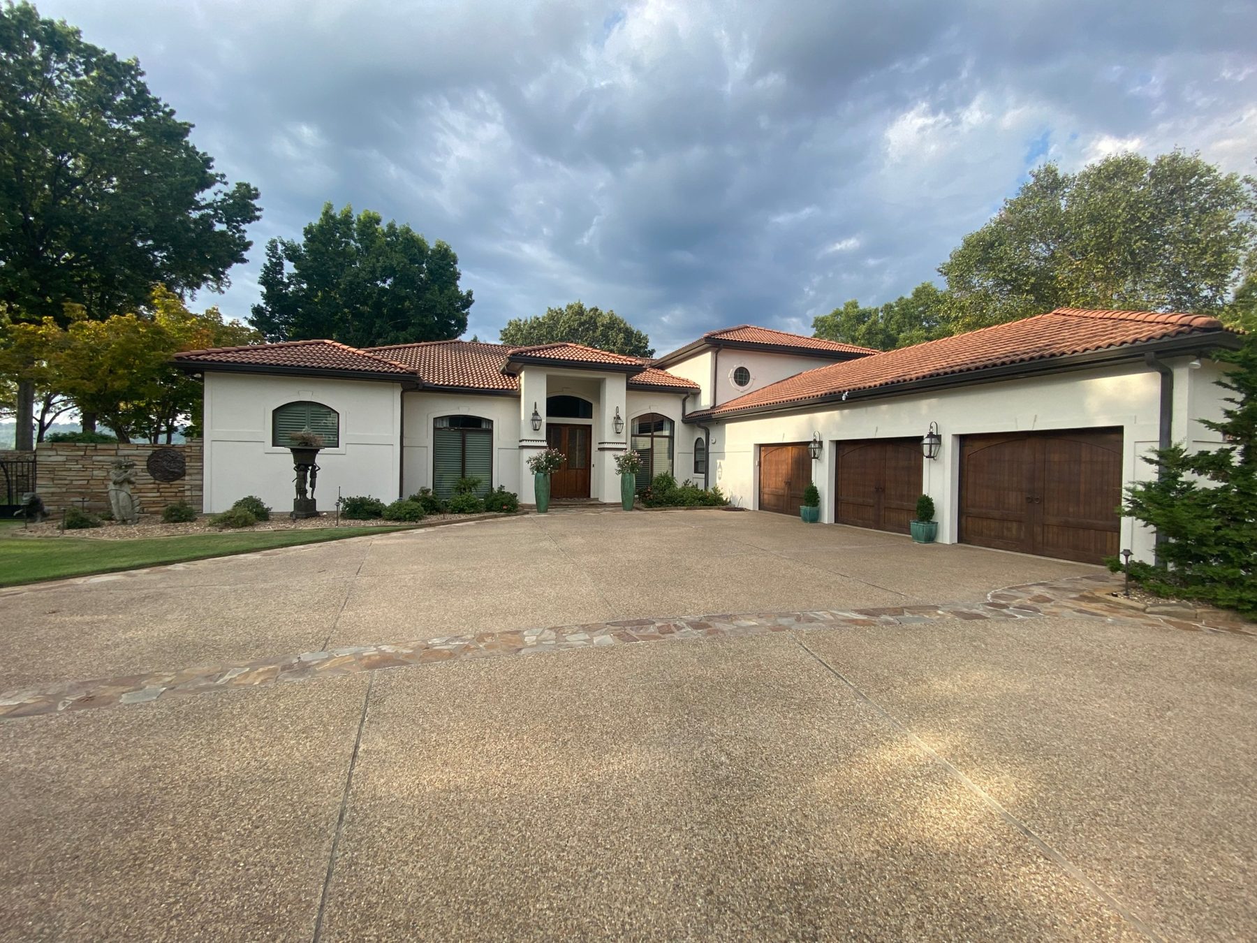 Stucco residence with clay tile roof, arched windows, and three cedar garage doors